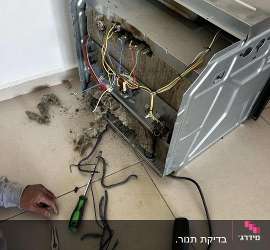 תנור פתוח עם חוטי חשמל, מברגה וכלי עבודה